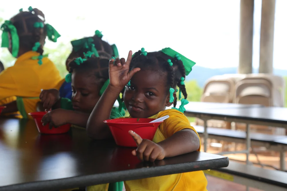 Children sitting together with red bowls at a school table